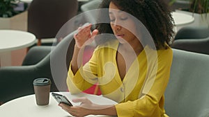 Unhappy African American woman in cafe holding head smartphone mobile phone cellphone notification sms message error