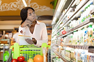 Unhappy African American Woman Holding Grocery Shopping List In Supermarket