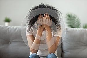 Unhappy African American woman holding head in hands, crying