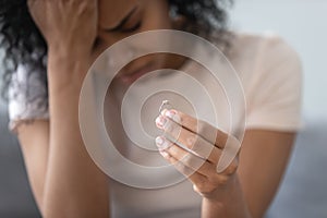 Unhappy African American woman holding wedding ring close up