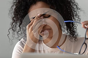 Unhappy African American woman taking off glasses, feeling eye strain