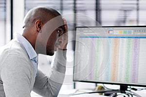 Unhappy African man using spreadsheets