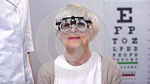 Unhappy aged woman in refractor squeezing eyes and shaking head, wrong diopter