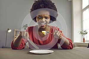 Unhappy angry screaming african american woman on diet looking at piece of apple