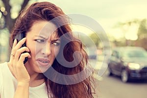 Unhappy angry young woman talking on mobile phone looking frustrated