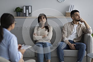 Unhappy arab spouses sitting at therapy session at marriage councellor's office, discussing their relationship problems