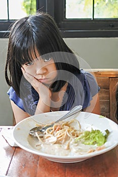 Unhappy Asian girl kid getting bored of food with appetite loss, no hungry habit, eating disorder