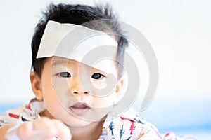 Unhappy Asian little baby sick with cool fever jel pad on forehead