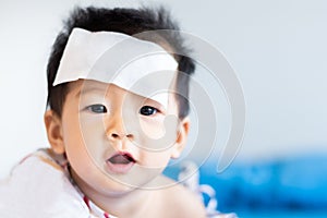 Unhappy Asian little baby sick with cool fever jel pad on forehead
