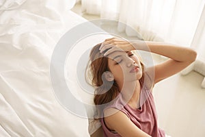 Unhappy asian woman touching hair sitting on home floor thinking about problems, upset girl feeling lonely and sad, psychological