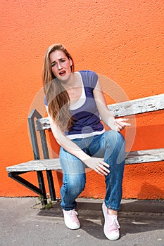 Unhappy beautiful girl sitting on a bench, begging, regretting something