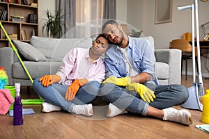 Unhappy Black Couple Cleaning House Together Sitting At Home