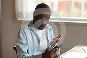 Unhappy black guy annoyed by spam message or broken device.