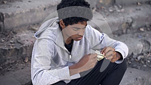 Unhappy black male holding dollar banknotes in hand, financial crisis, problem