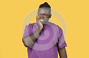 Unhappy black man suffering from tooth ache on yellow background