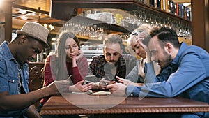 Unhappy, boring group of friends using smart phone during resting in the pub, bar.