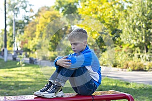 The unhappy boy sits. Bored or offended. Resentful boy