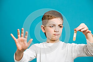 Unhappy boy in white clothes with adhesive plasters on his fingers photo