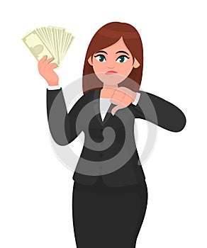 Unhappy business woman showing/holding bunch of money, cash, dollar, currency, banknotes in hand and gesturing, making thumbs down