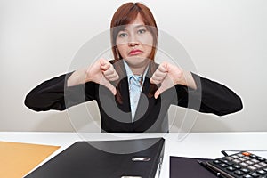 Unhappy business woman with thumb down in office - calculator, f