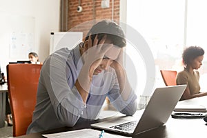 Unhappy businessman employee receive bad news, holding head in hands