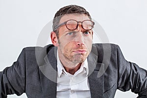 Unhappy businessman with eyeglasses on his forehead for suspicion