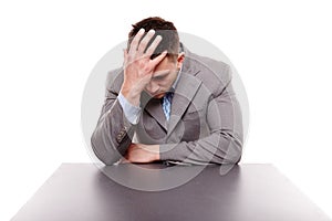 Unhappy businessman sitting at desk with hand on the head