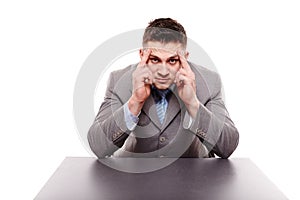 Unhappy businessman sitting at desk with hands on forehead