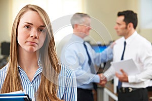 Unhappy Businesswoman With Male Colleague Being Congratulated