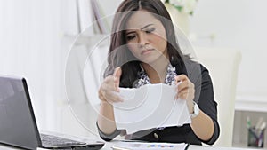 unhappy businesswoman reading her company paperwork at her offic