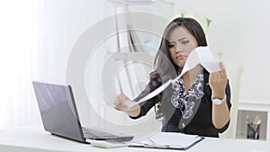 unhappy businesswoman reading her company paperwork at her offic