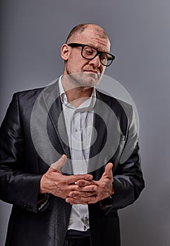 Unhappy busuness man in black suit and glasses showing the palm refusing sign on grey background. Closeup