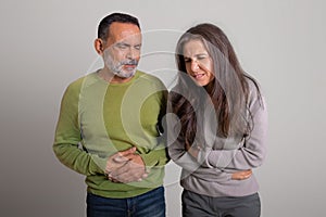 Unhappy caucasian elderly man and lady suffer from stomach and bell pain