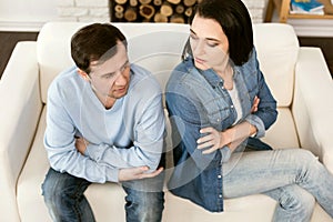 Unhappy cheerless couple sitting back to back