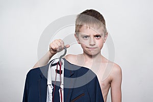 Unhappy child boy holds a business suit, school uniform. Young business boy is going to work
