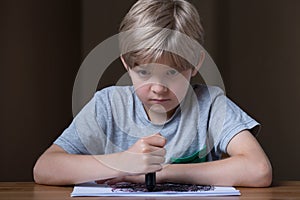 Unhappy child holding black crayon
