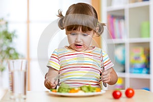 Unhappy child sitting at breakfast and uncertainty