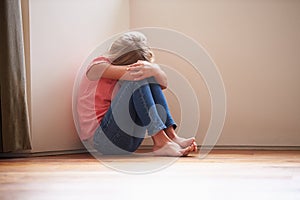 Unhappy Child Sitting On Floor In Corner At Home