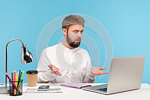 Unhappy confused man office worker spreading hands looking at laptop display with asking expression, dont know what to do,