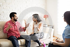 Unhappy couple fighting in front of psychologist