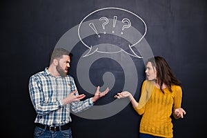 Unhappy couple quarreling over blackboard background