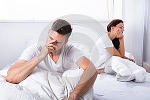 Unhappy Couple Sitting On Bed