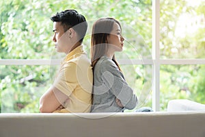 Unhappy Couple sitting behind each other on the couch and avoid talking or looking at each other, Cause of relationship problems