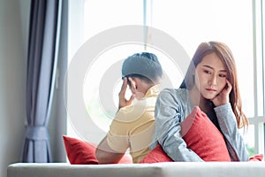 Unhappy Couple sitting behind each other on the couch and avoid talking or looking at each other, Cause of relationship problems