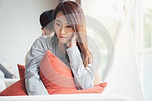 Unhappy Couple sitting behind each other on the couch and avoid talking or looking at each other, Cause of relationship problems