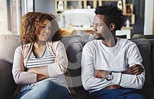 Unhappy couple talking about a breakup or problems in their relationship while sitting on a sofa at home together