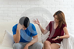 Unhappy couples home. Handsome man and beautiful young woman having quarrel. Sitting on white sofa together. Couple having