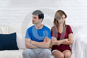 Unhappy couples home. Handsome man and beautiful young woman are sitting back to back on white sofa together. Couple having