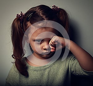 Unhappy crying kid girl in darkness. Closeup