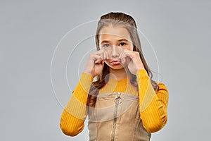 Unhappy crying teenage girl over gray background